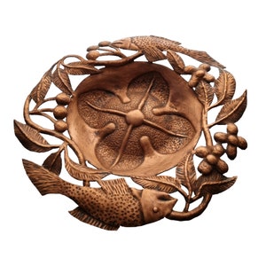 May include: A copper-colored metal dish with a decorative design of two fish and leafy branches. The dish has a textured surface and a raised center.