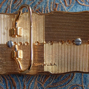 May include: Gold-tone belt buckle with a textured surface and a metal buckle. The buckle has the text "Made in USA" on the back.