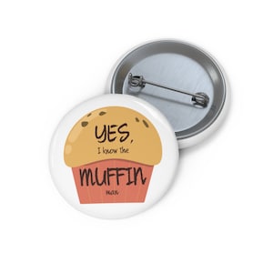 Puede incluir: Un botón blanco con un dibujo animado de un muffin. El muffin es marrón con chispas de chocolate y tiene el texto "YES, I know the MUFFIN man".
