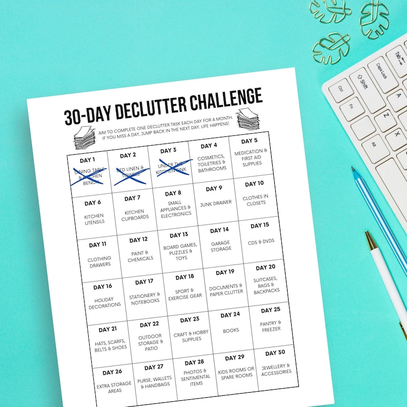 May include: A black and white printable 30-day declutter challenge chart. The chart is divided into 30 squares, each with a day number and a decluttering task. For example, Day 1 is "Dining Table & Bench", Day 2 is "Under the Kitchen Sink", Day 3 is "Small Appliances & Electronics", and so on.