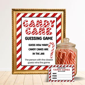 Op de afbeelding: Een ingelijst bord voor een "Candy Cane Guessing Game" met rood-witte gestreepte randen en tekst. Daarnaast staat een glazen pot gevuld met zuurstokken en een kleine spelkaart. De spelkaart heeft ruimte voor naam, telefoonnummer en gok.
