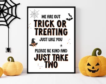 May include: A rectangular sign in a black frame with white background and black text reading WE ARE OUT TRICK OR TREATING JUST LIKE YOU PLEASE BE KIND AND JUST TAKE TWO. Decorated with a spider web, spider, bat, witch hat, and small stars.