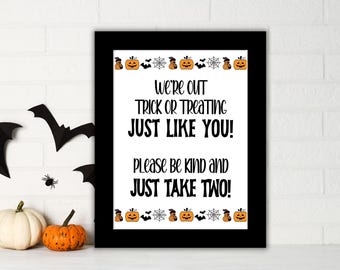 May include: A framed Halloween sign with the text "We're OUT TRICK OR TREATING JUST LIKE YOU! Please be kind and JUST TAKE TWO!" The sign has a black border and is decorated with pumpkins, bats, and spiderwebs.