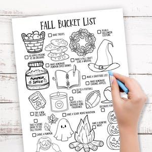 May include: Black and white Fall Bucket List printable with illustrations of fall activities. Includes text such as "Pumpkin Spice", "Bonfire Night", and "Carve a Pumpkin". A hand with a blue pen is pointing to the "Make a gratitude list" box.