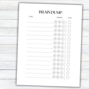 May include: A white paper titled "BRAIN DUMP" with task lines, priority circles (H, M, L), and "DONE" check boxes. The paper is on a white wooden surface. The design is minimalist and suitable for organizing tasks.