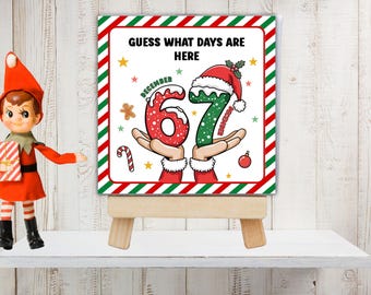 Könnte beinhalten: Ein quadratisches Schild auf einer Holzstaffelei mit dem Text GUESS WHAT DAYS ARE HERE und den Zahlen 67 in Rot und Grün mit Schneeakzenten. Das Design enthält Weihnachtsmannhände, eine Zuckerstange, einen Lebkuchenmann und eine rote Christbaumkugel.