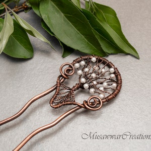 Peut inclure: Bâtonnet à cheveux en fil de cuivre avec un motif d'arbre et des perles blanches. L'arbre est fait de fil et a une forme circulaire. Le bâtonnet à cheveux est un accessoire décoratif pour les cheveux.