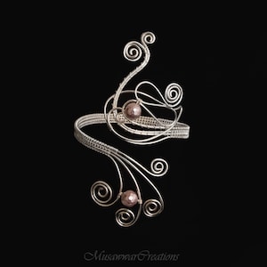 May include: Silver wire bracelet with a delicate, floral design and two small, round, iridescent purple stones.