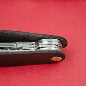 May include: A black leather key holder with a brass screw and multiple keys inside.