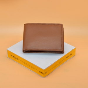 May include: A brown leather wallet on a white box with yellow text that says "KARTIRA" on both sides.