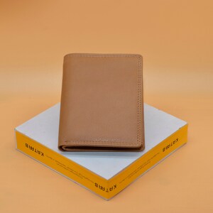 May include: A brown leather wallet on a white box with the word "KARTIR" printed on the side in yellow.