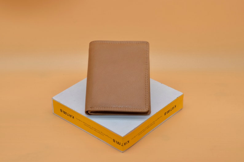 May include: A brown leather wallet on a white box with the word "KARTIR" printed on the side in yellow.