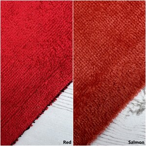 May include: Two close-up images of fabric swatches. The first swatch is a bright red terry cloth fabric. The second swatch is a salmon coloured terry cloth fabric.