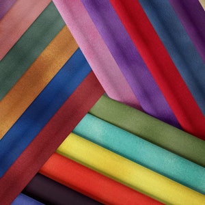 Op de afbeelding: Een verzameling stofstalen in verschillende kleuren, waaronder rood, blauw, groen, geel en bruin. De stofstalen zijn in een diagonaal patroon gerangschikt, wat een visueel aantrekkelijk display creëert.