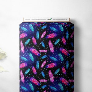 May include: Black fabric with a repeating pattern of colourful feathers and white dots. The feathers are pink, blue, and teal with intricate designs. The fabric has a gradient background that fades from dark blue to black.