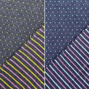 May include: Two fabric swatches with different patterns. The left swatch is a dark grey fabric with small pink and yellow dots. The right swatch is a light blue fabric with small pink and white dots. Both swatches are cut diagonally to reveal a striped fabric underneath. The striped fabric on the left is dark grey with pink and yellow stripes. The striped fabric on the right is light blue with pink and white stripes.