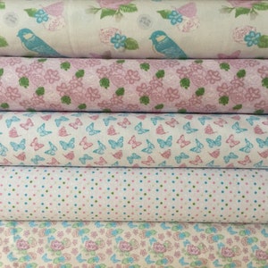 May include: A stack of fabric rolls featuring various patterns. The patterns include blue birds, pink roses, butterflies, and polka dots. The fabrics are in shades of pink, blue, green, and white, creating a soft and feminine aesthetic.