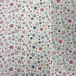 May include: A fabric with a white background and a repeating pattern of colorful stars. The stars are outlined in black and filled with various patterns, including stripes, polka dots, and checkered designs.