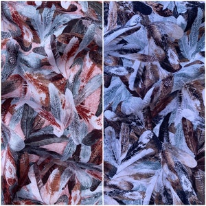 May include: A fabric with a repeating pattern of abstract leaves in shades of brown, blue, and white. The leaves are layered and overlapping, creating a sense of depth and texture.