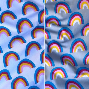 Könnte beinhalten: Blauer Stoff mit einem sich wiederholenden Muster aus bunten Regenbögen. Die Regenbögen sind blau umrandet und mit rosa, gelb und weiß gefüllt.