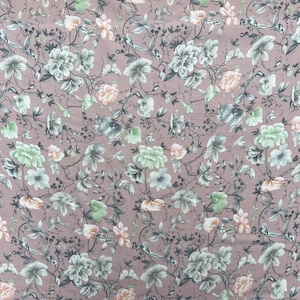 May include: A pink fabric with a floral pattern. The flowers are in shades of green, white, and pink. The fabric has a delicate, vintage feel.