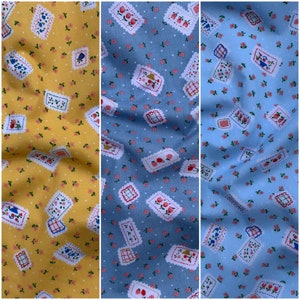 May include: Three fabric swatches with a repeating pattern of small pink flowers and a larger design of a white rectangle with a red and blue floral design. The swatches are yellow, blue, and light blue.