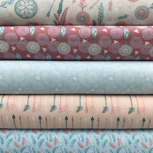 Puede incluir: Cuatro rollos de tela con diferentes patrones. El rollo superior tiene un fondo blanco con un diseño de atrapasueños azul verdoso y blanco. El segundo rollo tiene un fondo rosa con un patrón geométrico azul verdoso y blanco. El tercer rollo tiene un fondo azul claro con un patrón de remolino blanco. El rollo inferior tiene un fondo rosa claro con un patrón de flecha azul verdoso y blanco.