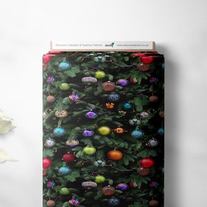 Może przedstawiać: Rolka materiału z motywem choinki. Materiał pokryty jest kolorowymi ozdobami w odcieniach czerwieni, zieleni, niebieskiego, fioletu i złota. U góry widnieje napis "Discover Lifestyle & Fashion Fabrics".