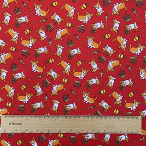May include: Red fabric with a repeating pattern of cartoon corgis wearing crowns. The corgis are in various poses, some sitting, some standing, and some running. There are also gold crowns, scepters, and balls scattered throughout the pattern.