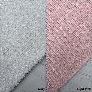May include: Two fabric swatches, one ivory and one light pink. Both swatches are made of a soft, textured material.