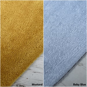 May include: Two fabric swatches, one mustard yellow and one baby blue. The fabric is soft and fluffy, with a textured surface.