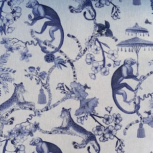 K&ouml;nnte beinhalten: Blauer und wei&szlig;er Blumenstoff mit Affen und Leoparden. Der Stoff hat ein sich wiederholendes Muster aus Affen, Leoparden und Blumen auf hellblauem Hintergrund.