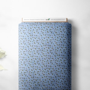 May include: A blue fabric with a repeating pattern of small, colorful pencils. The fabric is rolled up and has a wooden label that says "Discover Lifestyle & Fashion Fabrics" and "www.discoverdirect.co.uk".