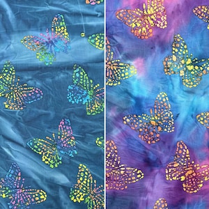 Pode incluir: Um tecido azul e roxo com um padrão tie-dye apresentando silhuetas de borboletas coloridas.