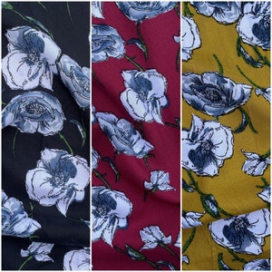 May include: Three fabric swatches with a floral pattern. The fabric on the left is black with white flowers. The fabric in the middle is red with white flowers. The fabric on the right is yellow with white flowers.