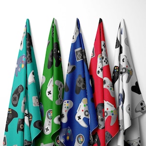 May include: Five colorful fabric towels with a repeating pattern of video game controllers. The towels are turquoise, green, blue, red, and white.