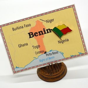 May include: A map of Benin with a gold pin featuring the Beninese flag. The map shows the country's borders with Burkina Faso, Niger, Nigeria, Togo, and Ghana. The map also shows the cities of Cotonou and Porto-Novo.