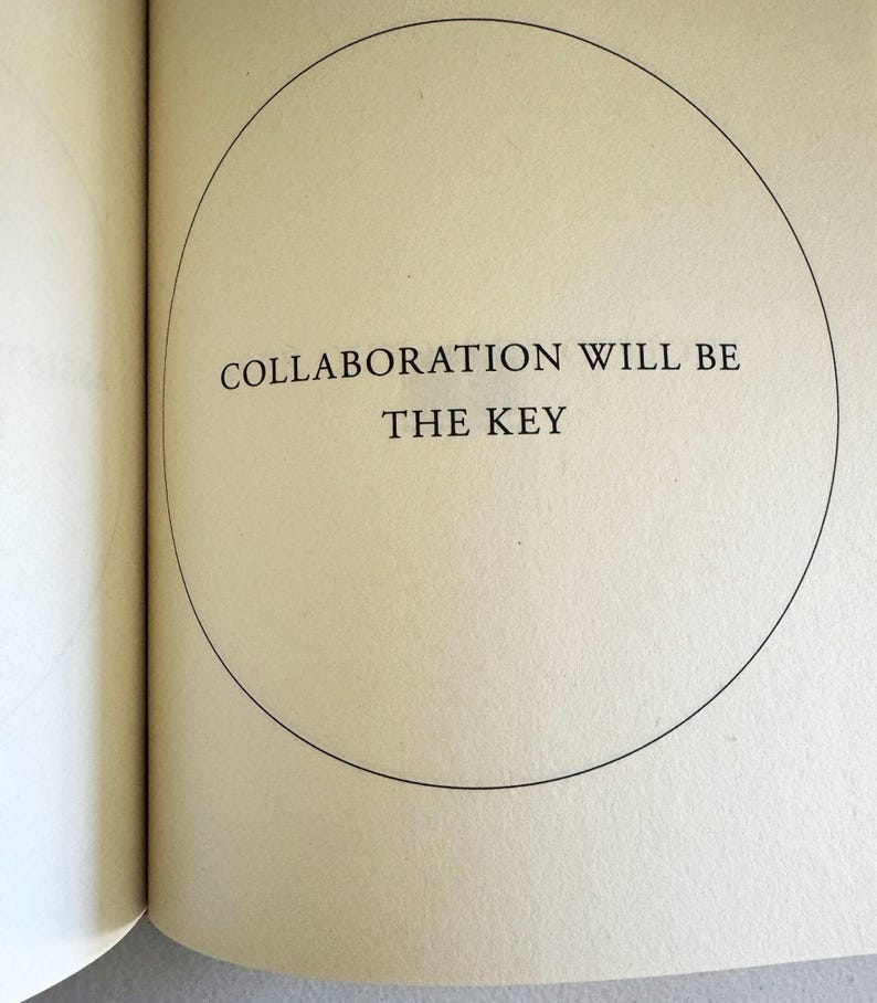 May include: Open book page with the text "COLLABORATION WILL BE THE KEY" inside a black circle. The text is in a serif font and is centered on the page. The page is a light beige color.