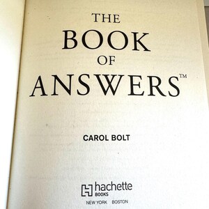 May include: Open book page with the title "THE BOOK OF ANSWERS" in large, bold black font. The author's name, Carol Bolt, is below the title. The Hachette Books logo and the city names New York and Boston are at the bottom.
