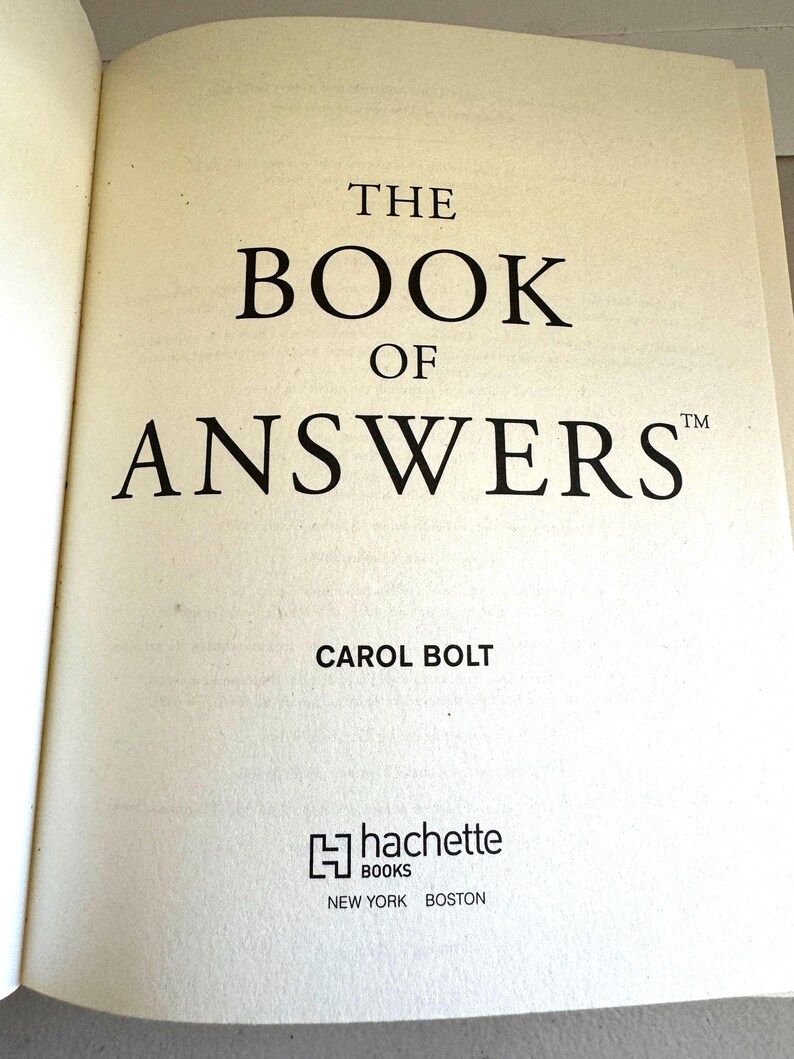 May include: Open book page with the title "THE BOOK OF ANSWERS" in large, bold black font. The author's name, Carol Bolt, is below the title. The Hachette Books logo and the city names New York and Boston are at the bottom.