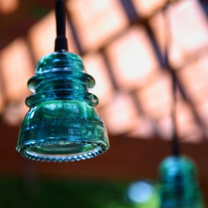 Peut inclure: Un luminaire suspendu en verre bleu turquoise avec un design arrondi &agrave; plusieurs niveaux. La lumi&egrave;re est suspendue &agrave; un cordon noir.