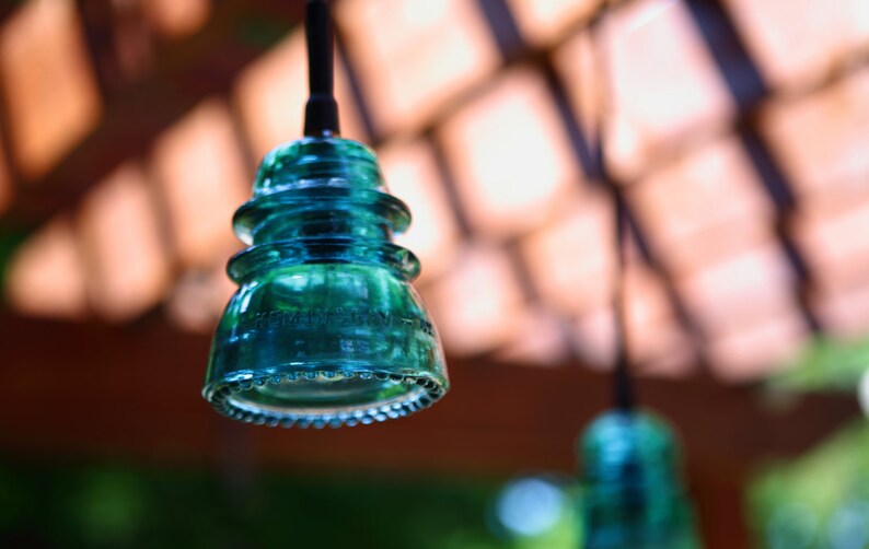 Peut inclure: Un luminaire suspendu en verre bleu turquoise avec un design arrondi &agrave; plusieurs niveaux. La lumi&egrave;re est suspendue &agrave; un cordon noir.