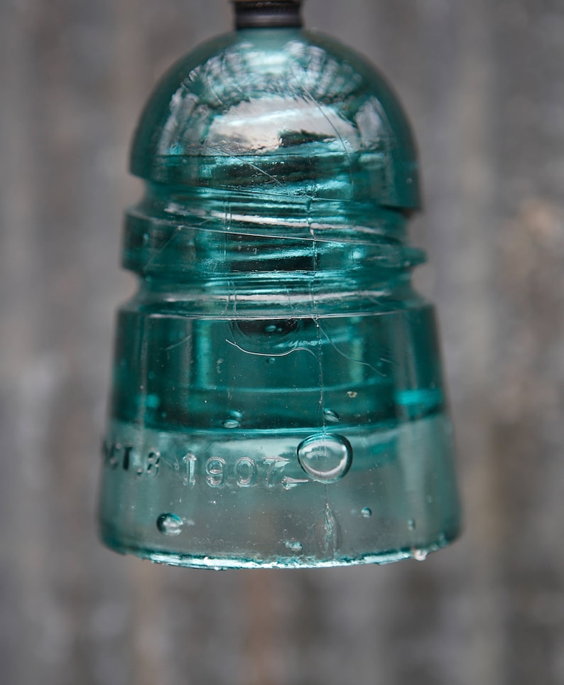 K&ouml;nnte beinhalten: Ein antiker gr&uuml;ner Glasisolatoren mit dem Datum "Oct. 13 1907" auf der Unterseite.