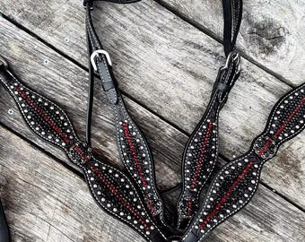 May include: Black leather horse tack set with white stitching, red accents, and silver studs. The set includes a headstall, breast collar, and reins, all designed with a decorative pattern.