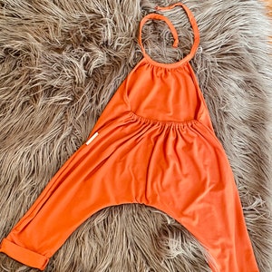 May include: A rust-colored halter jumpsuit with a gathered waist and cuffed legs. The jumpsuit is made of a soft, stretchy fabric and is perfect for lounging or running errands.