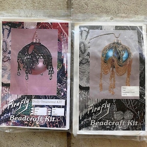 May include: Two Firefly Beadcraft Kits. One kit features a pink ornament with black beading and the text "Doily Ornamental KIT". The other kit shows a teal ornament with gold beading and the text "Deco Teal Ornament Cover 15076".