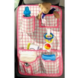 May include: A rectangular car seat organizer featuring a white and pink grid pattern with multiple storage pockets. The organizer holds a blue plastic bottle, a brown teddy bear, a colorful ring toy, a small ball, and folded white cloths.
