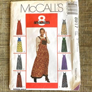 May include: A McCall's 8917 sewing pattern envelope for a floor-length jumper dress with a square neckline and wide straps. The cover features a central photograph of a person wearing a brown floral jumper and eight illustrations of variations.