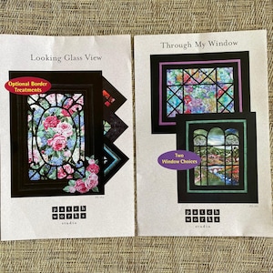 May include: Two white paper pattern sheets from Patch Works Studio. The left sheet titled Looking Glass View features a floral window design with an Optional Border Treatments label. The right sheet titled Through My Window shows two landscape window designs with a Two Window Choices label.