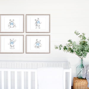 May include: Four framed prints of a white teddy bear wearing a blue bow tie. The prints are arranged in a grid on a white wall. A white crib and a vase of greenery are in the background.